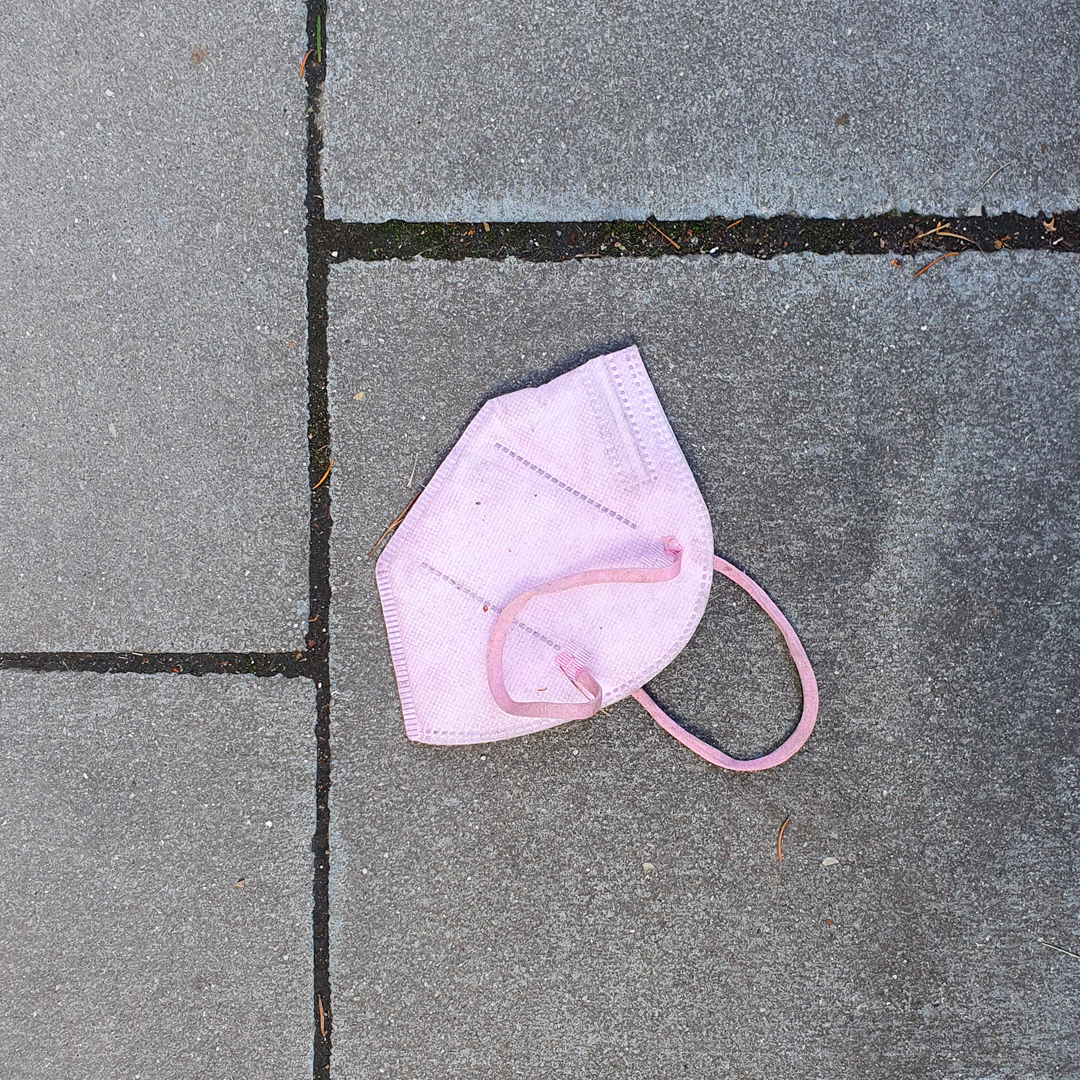 Eine pinke FFP2 Maske liegt auf dem Boden. Die Aufschrift lautet masken.abgesang.